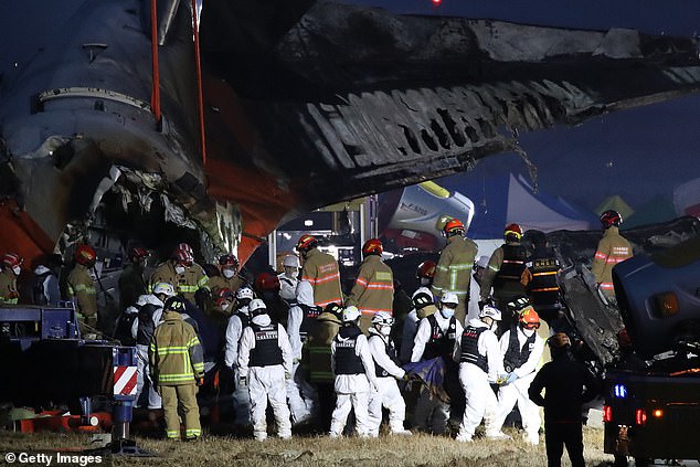 Firefighters carry the body of a passenger from the wreckage of a passenger plane at Muan International Airport on December 29, 2024