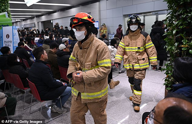 Firefighters walk past people and relatives of passengers of the crashed Jeju Air Boeing 737-800 series aircraft react at Muan International Airport in South Jeolla Province