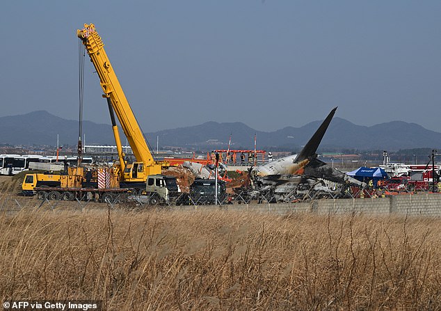 Firefighters and rescue team members work near the wreckage of a Jeju Air Boeing 737-800 series aircraft - December 29, 2024