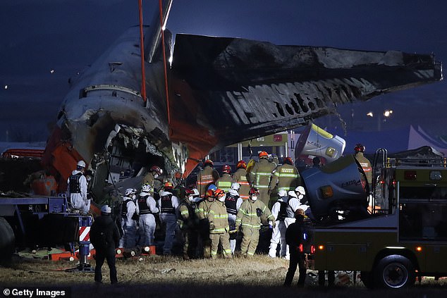 Firefighters carry the body of a passenger from the wreckage of a Jeju Air plane at Muan International Airport - December 29, 2024