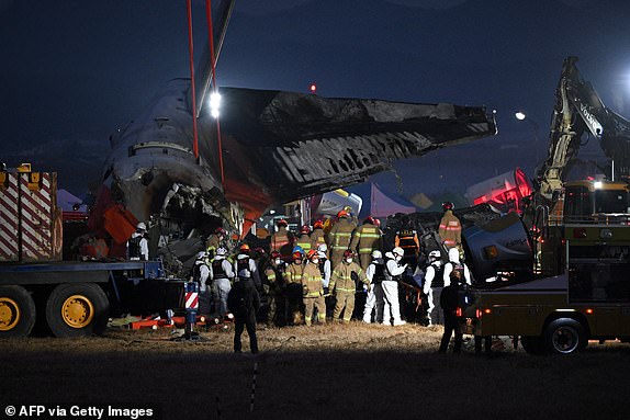 Firefighters and rescue personnel carry the body of a victim near the scene where a Jeju Air Boeing 737-800 series aircraft crashed and burst into flames at Muan International Airport in South Jeolla Province, some 288 kilometres southwest of Seoul on December 29, 2024. A Jeju Air plane carrying 181 people from Thailand to South Korea crashed on arrival, smashing into a barrier and bursting into flames, leaving all but two feared dead. (Photo by Jung Yeon-je / AFP) (Photo by JUNG YEON-JE/AFP via Getty Images)