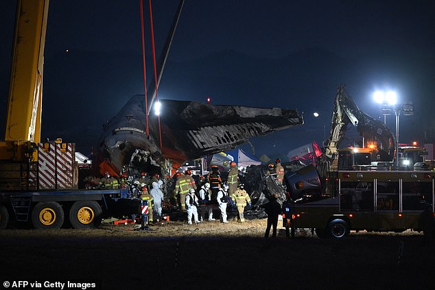 Firefighters and rescue personnel carry the body of a victim near the scene where a Jeju Air Boeing 737-800 series aircraft crashed