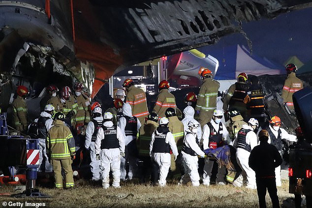 Firefighters carry the body of a passenger from the wreckage of the Boeing 737-800