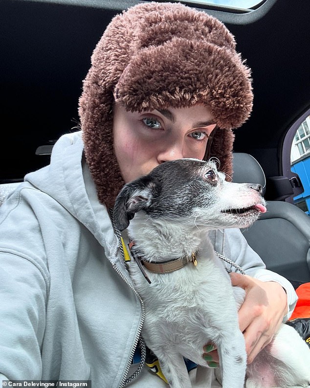 Cara also snuggled up to her dog as she wrapped up for the cold in another snap