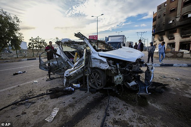 Palestinians inspect a car targeted in an overnight Israeli airstrike that killed its occupants in the town of Khan Younis