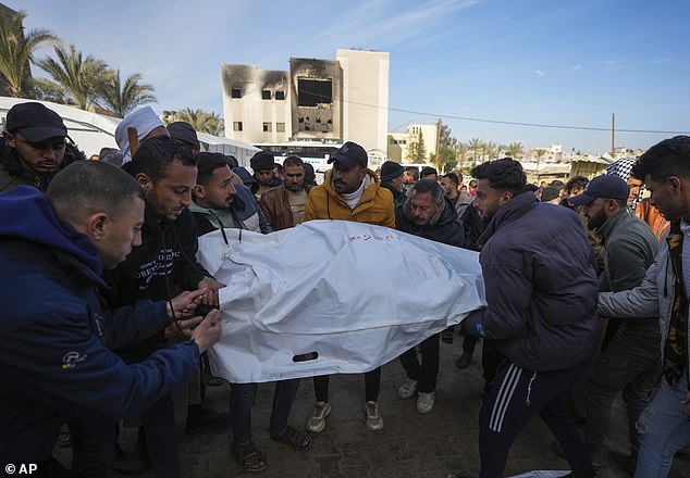 Palestinians carry white sacks containing the bodies of those killed in overnight Israeli airstrikes on the Khan Younis refugee cam