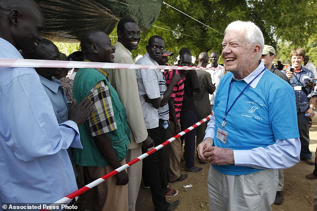 FILE - Former U.S. President Jimmy Carter, right, greets Southern Sudanese men waiting to cast their vote at a polling station in Juba, Southern Sudan, Jan 9, 2011, during a weeklong referendum on independence that is expected to split Africa's largest nation in two. (AP Photo/Jerome Delay, File)