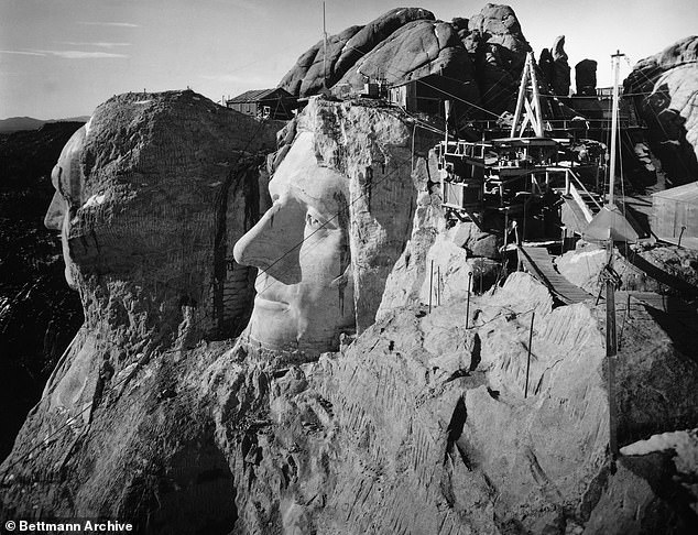 Carvers are seen working on the enormous sculpture. The head of Washington and Jefferson from the top of Lincoln's head