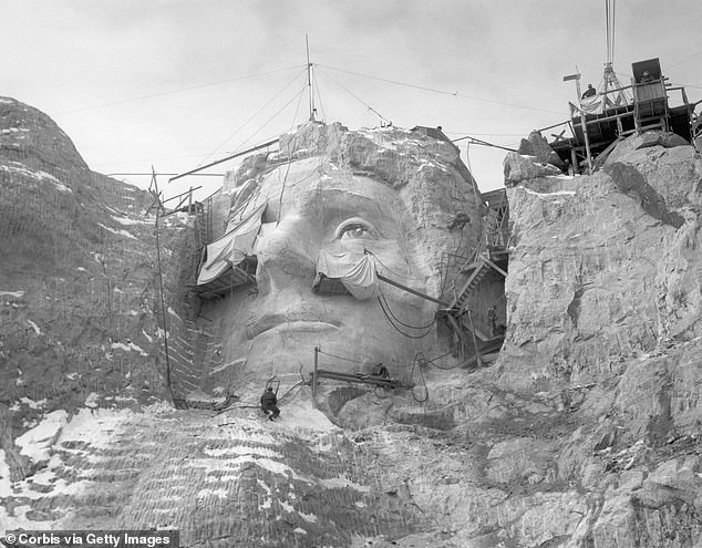 Stone carvers are seen on scaffolding and hoists carving the face of Thomas Jefferson into Mount Rushmore