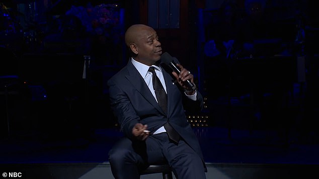 While sitting on a stool and smoking a cigarette, Chappelle initially joked that the only reason he agreed to host Saturday Night Live again was to burn off old Trump jokes