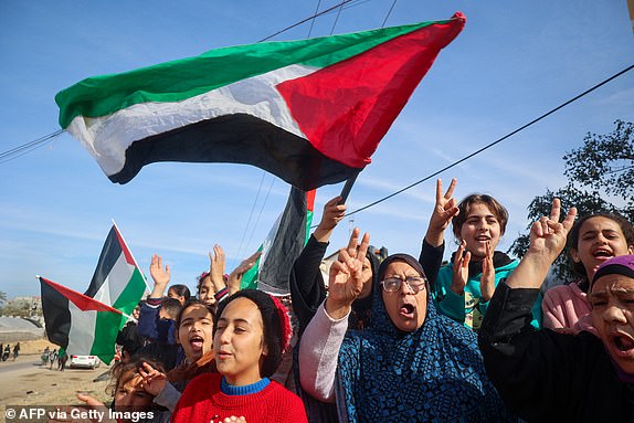 TOPSHOT - Displaced Palestinians wave national flags as they return to Rafah, in the southern Gaza Strip, on January 19, 2025, following a ceasefire deal in the war between Israel and Hamas. (Photo by Eyad BABA / AFP) (Photo by EYAD BABA/AFP via Getty Images)