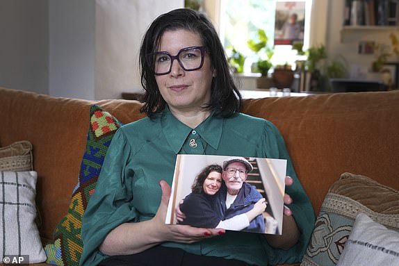 Sharone Lifschitz holds a photograph of herself with her father, Oded Lifshitz, who was abducted by Hamas militants, at her home in London, Friday, Jan. 17, 2025. (AP Photo/Kirsty Wigglesworth)