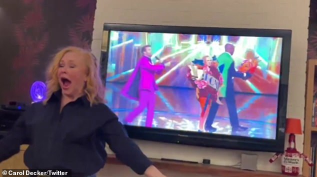 In the background, the episode of The Masked Singer was on the screen and Carol reenacted her unmasking as she removed the masked from her head