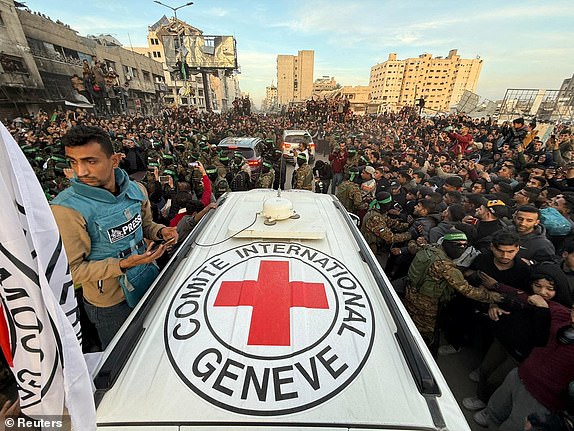 Palestinian Hamas militants and people gather around a Red Cross vehicle before the release of hostages kidnapped during the October 7, 2023, attack on Israel by Hamas, as part of a ceasefire and a hostages-prisoners swap deal between Hamas and Israel, in Gaza City, January 19, 2025. REUTERS/Dawoud Abu Alkas