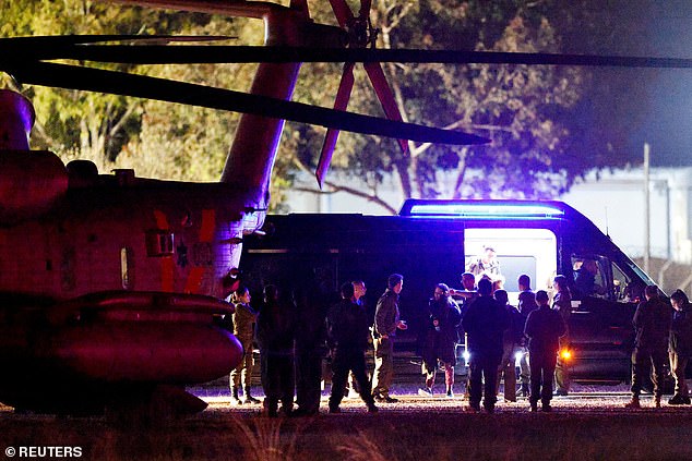 People walk towards Israeli military helicopters as Romi Gonen, Doron Steinbrecher and Emily Damari are released