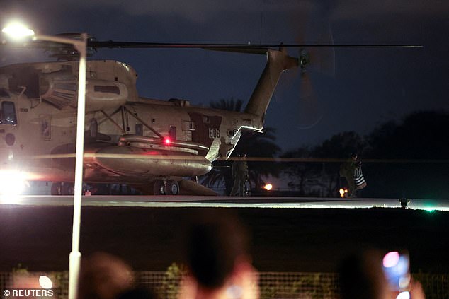 People walk near a helicopter carrying Romi Gonen, Doron Steinbrecher and Emily Damar