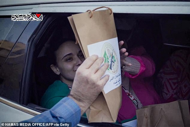 Their smiles instantly dropped as they were handed brown paper bags with the Hamas logo printed on the side, and forced to hold them up and pose for the camera