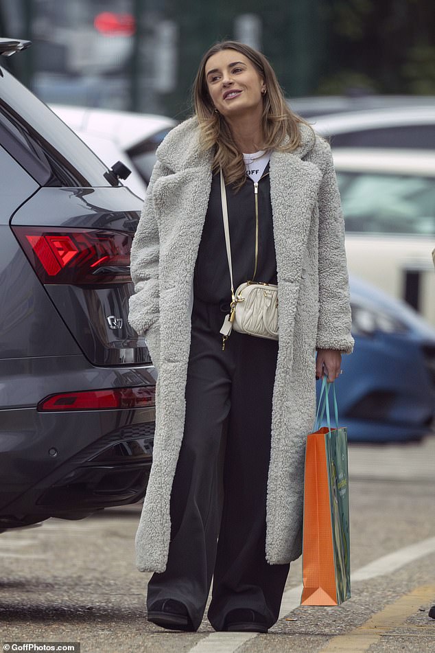 Dani was casually clad for the outing, layering a grey teddy bear coat over a navy jumpsuit and accessorising with a white Miu Miu bag