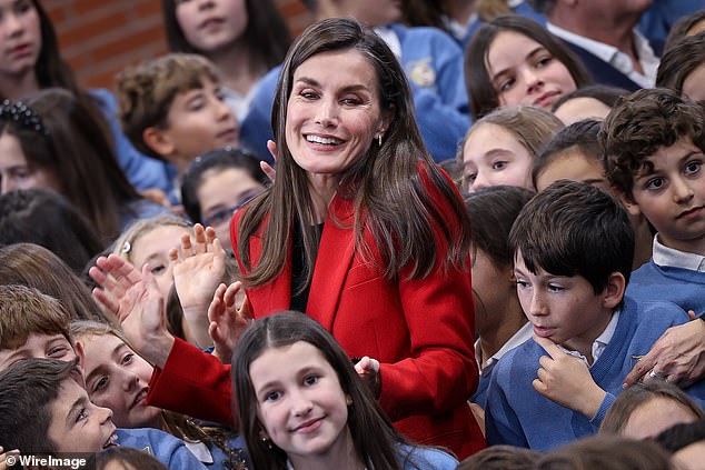 Queen Letizia smiles as she is swamped with children at the Cortes de Cadiz school on Thursday