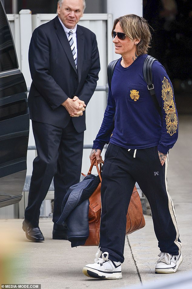 The country singer dressed casually for the flight in black track pants and a navy shirt with a gold design on the sleeve