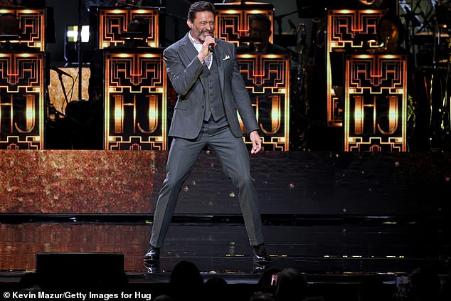 Dressed for the stage in a smart grey lounge suit with a matching vest and a white shirt, a bearded Hugh can be seen pouring his heart into his performance