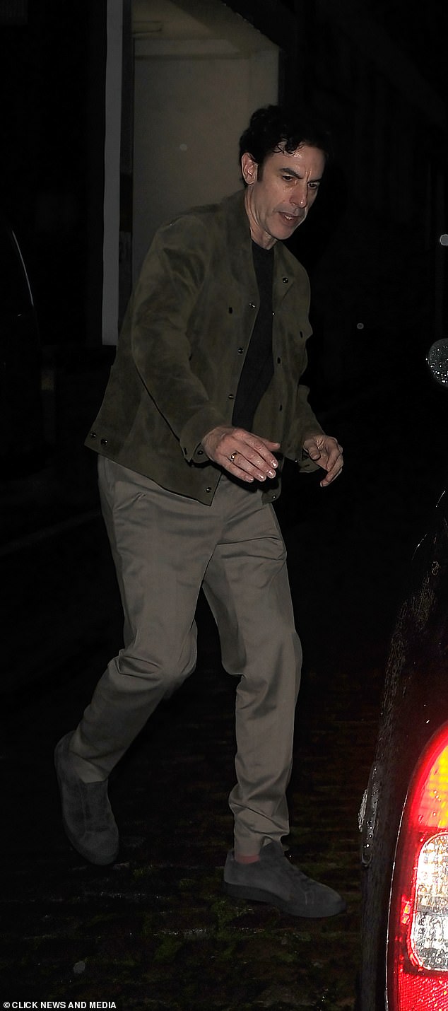 Sacha Baron Cohen looked cool in a suede brown coat and khaki trousers