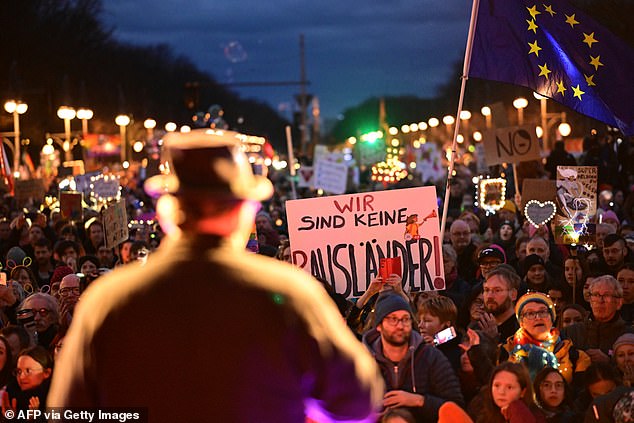 Participants gather for a demonstration against a political shift to the right to stand together during a 'Sea of Lights for Democracy' in front of the landmark Brandenburg Gate in Berlin on January 25, 2025