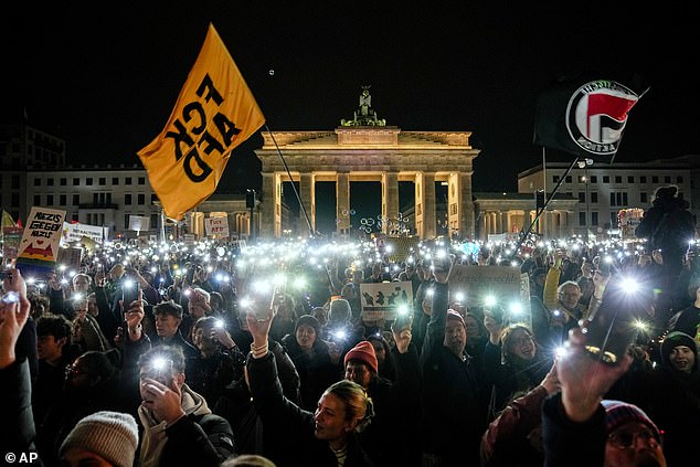 People hold up their cell phones as they protest the far-right Alternative for Germany, or AfD party, and right-wing extremism in front of the Brandenburg Gate in Berlin, Germany, Saturday, Jan. 25, 2025