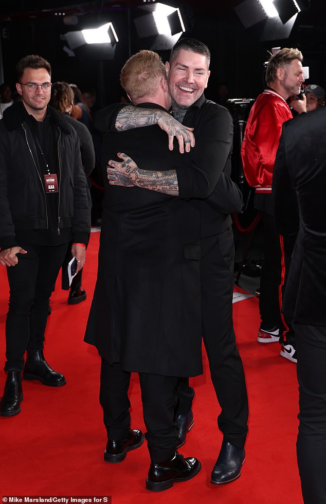 The two singers broke into laughter as they wrapped their arms around each other, before joining bandmate Keith to pose for photos and speak to the press