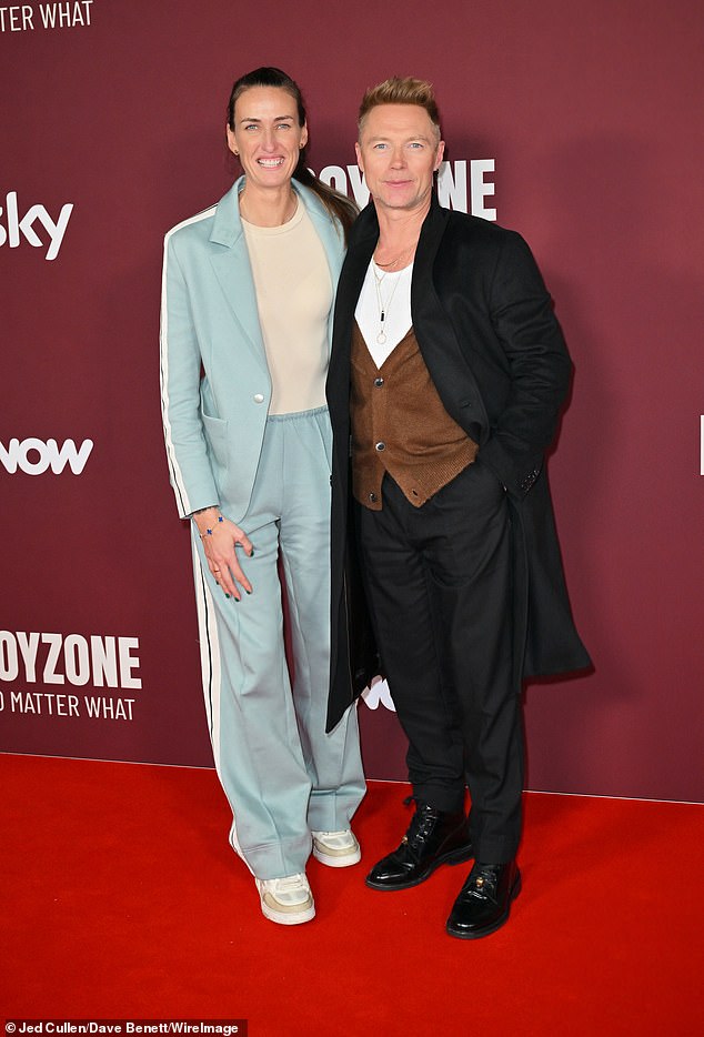 Ronan looked handsome for the premiere, wearing a pair of smart black trousers and a matching long tailored coat over of brown button-up cardigan