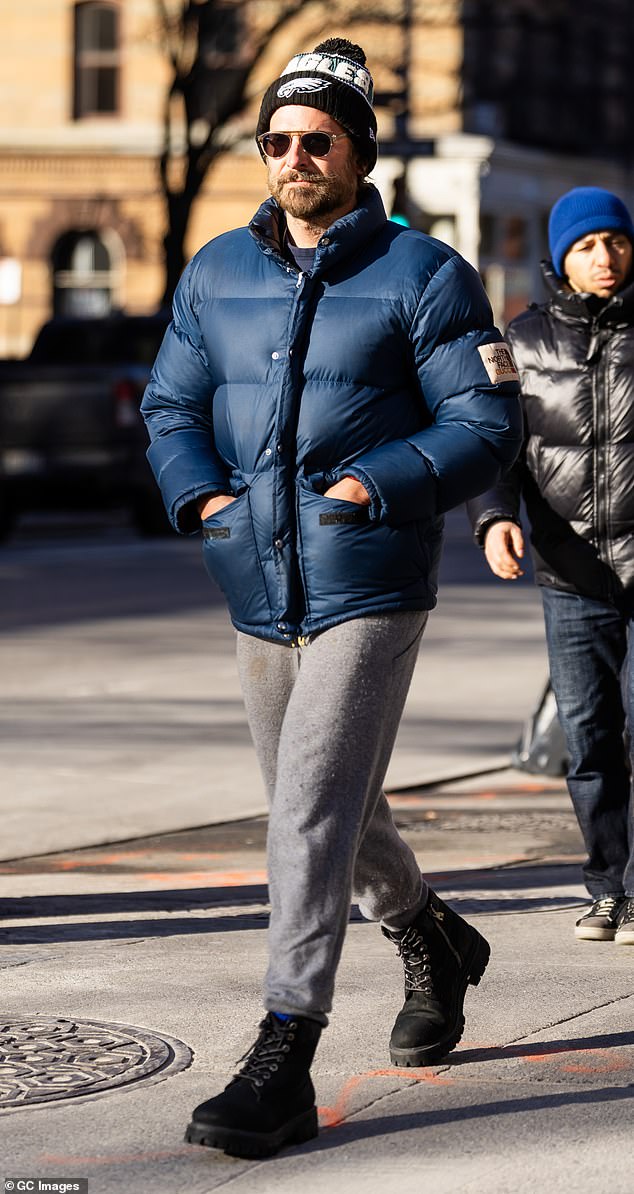 The Maestro director bundled up in a dark blue puffer jacket and looked cozy in a pair of light gray joggers and black work boots