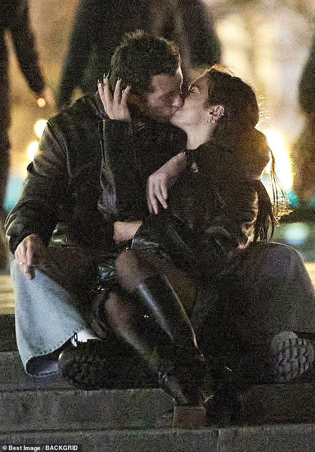 The newly engaged couple embrace on steps in front of the Eiffel Tower