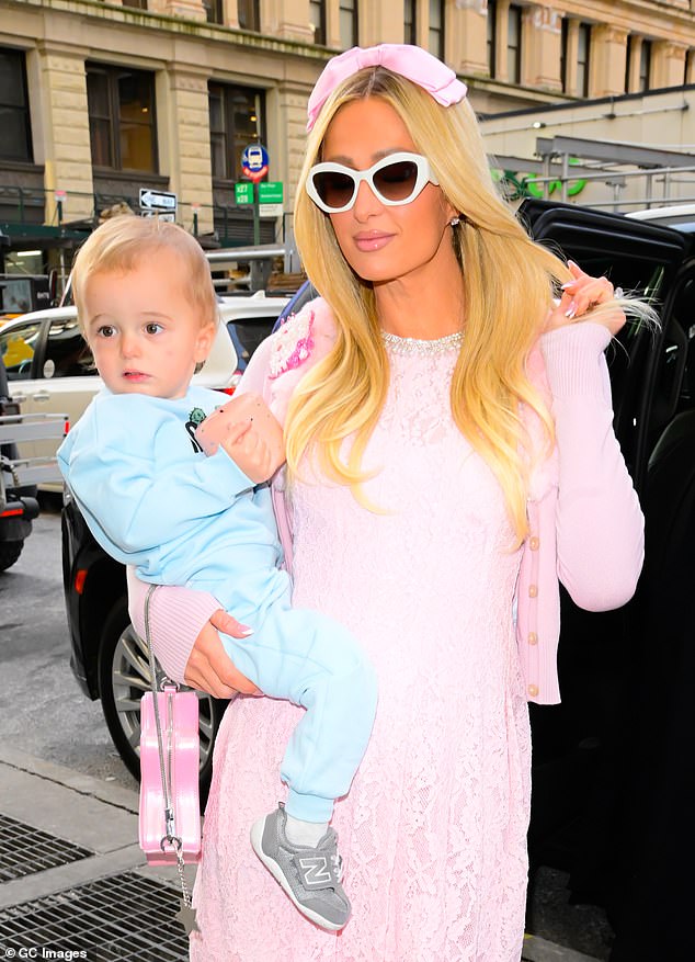 Hilton looked effortlessly chic in a pink lace frock while holding her son on her hip