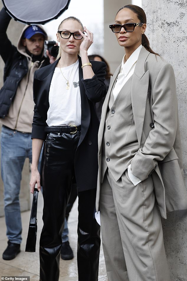 Joan rocked a crisp white shirt under the waist coat and jacket as she posed for photos leaning against a wall wearing a pair of sunglasses