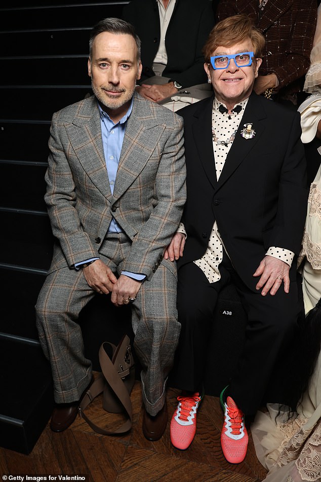 Elton John put on a stylish display in bold blue glasses and white and black polka dot shirt as he joined his  husband David Furnish at Valentino show during Paris Fashion Week on Wednesday