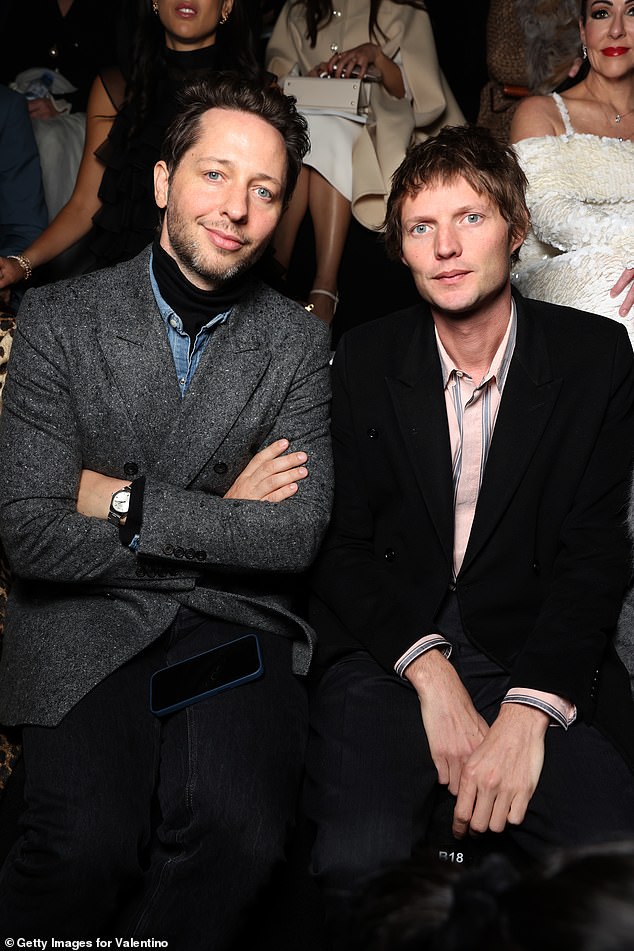 The British photographer looked incredibly dapper in a pale pink and blue striped shirt which he paired with a smart black wool coat