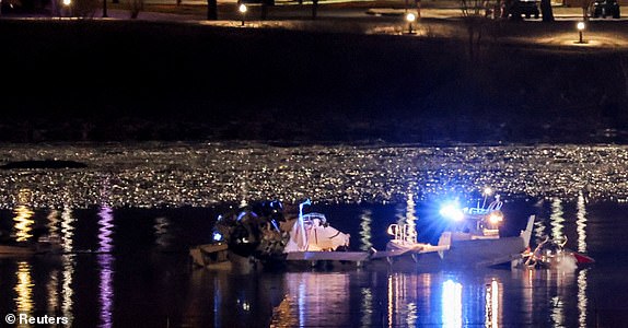 Emergency personnel and divers work next to parts of the wreckage of the American Eagle flight 5342, after it collided with a Black Hawk helicopter while approaching Reagan Washington National Airport and crashed into the Potomac River, outside Washington, U.S., January 30, 2025. REUTERS/Carlos Barria