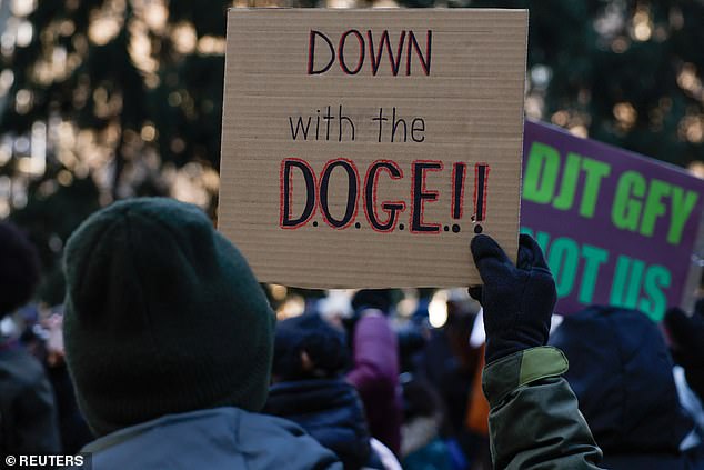 A protester holds a sign as demonstrators gather in protest of U.S. President Donald Trump outside New York's City Hall, in New York City