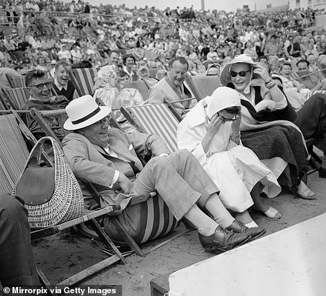 In this humorous image, taken in 1960, holidaymakers on Bognor Regis beach laugh as one tourist's deckchair collapses under his weight