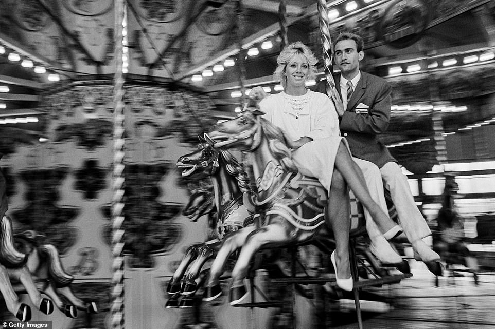 A holidaymaker and Redcoat entertainer ride the merry-go-round at Butlin's in Bognor Regis in 1985