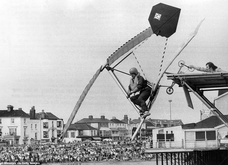 In this image, a hopeful competitor is shown attempting to fly in the Bognor Regis International Birdman contest in 1979. Contestants would compete to see who could fly through the air the furthest after jumping off the end of the pier