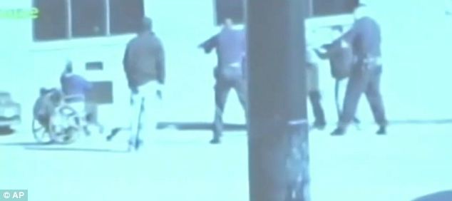 Under fire: A grab from grainy mobile phone video footage shows police in San Francisco aiming their guns at a man in a wheelchair who allegedly stabbed an officer