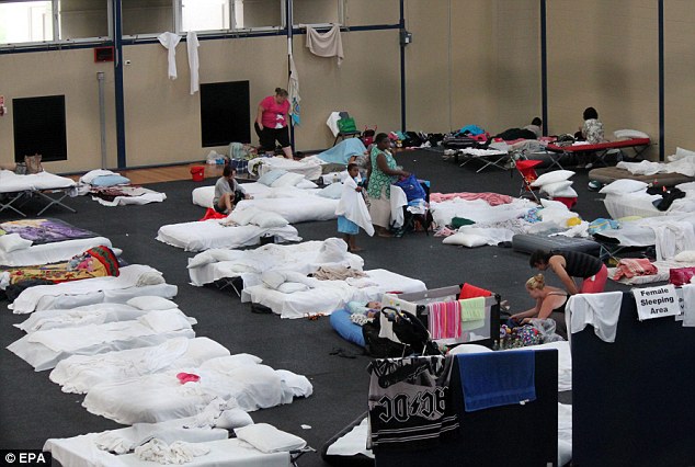 Rescued: Families slept on beds at a sports centre at Central Queensland University after they were evacuated from their homes