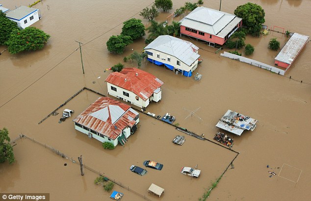 No respite: An aerial view shows homes surrounded by muddy waters, with cars virtually submerged