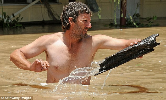 Clean up: A man clears debris from the front of his home in Rockhampton. River levels had begun to recede, but more heavy rain could stop people returning home