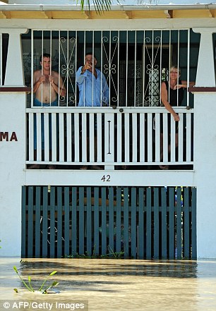 On guard: Residents remain in their flooded home to stop looters breaking in and, right,