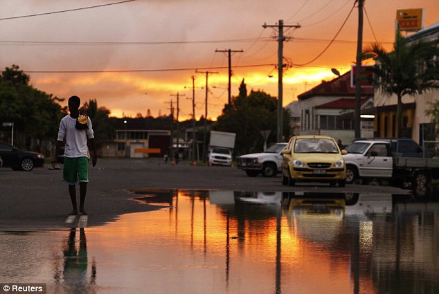 Aftermath: A man walks along a flooded street in the Depot Hill area of the city. The Fitzroy River has begun to recede