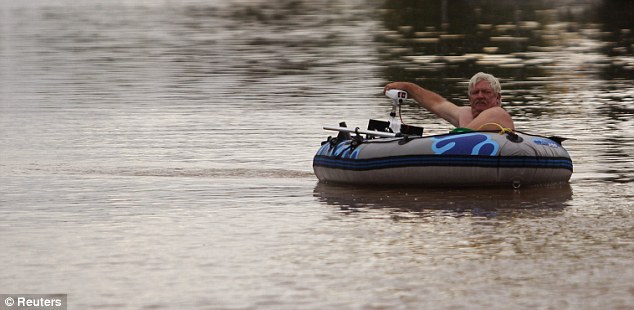 Misery: A man navigates the streets in Rockhampton in a dinghy. The worst floods for decades have devastated Queensland