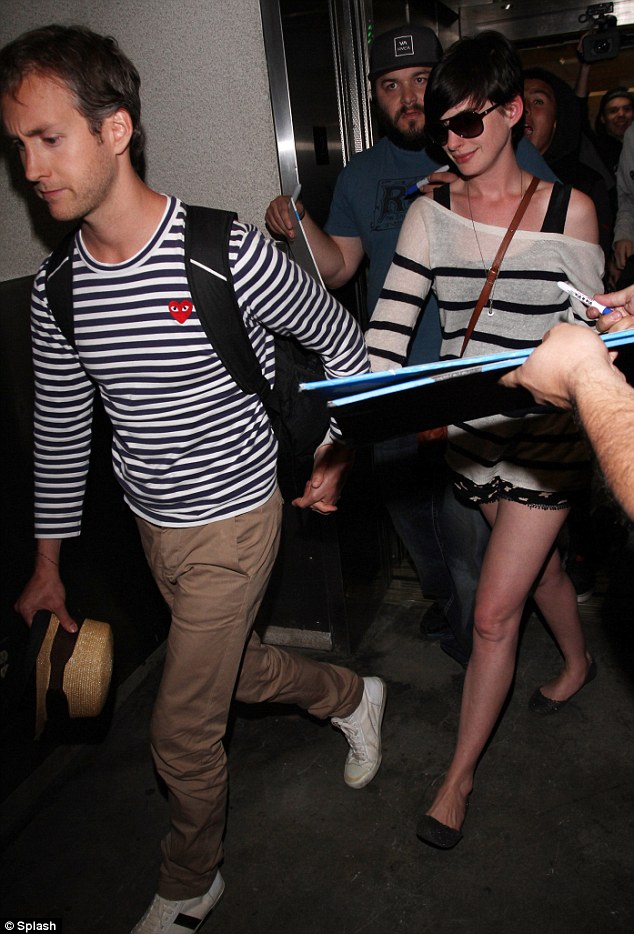 Follow me: Hathaway's protective husband took her hand as he led her out of the busy airport