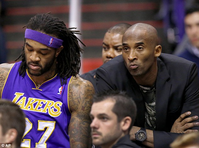 Injured Los Angeles Lakers player Kobe Bryant (right) sits on the end of the team bench next to Jordan Hill, during the first half of an NBA basketball game against the Phoenix Suns on Wednesday January 15, 2014, in Phoenix